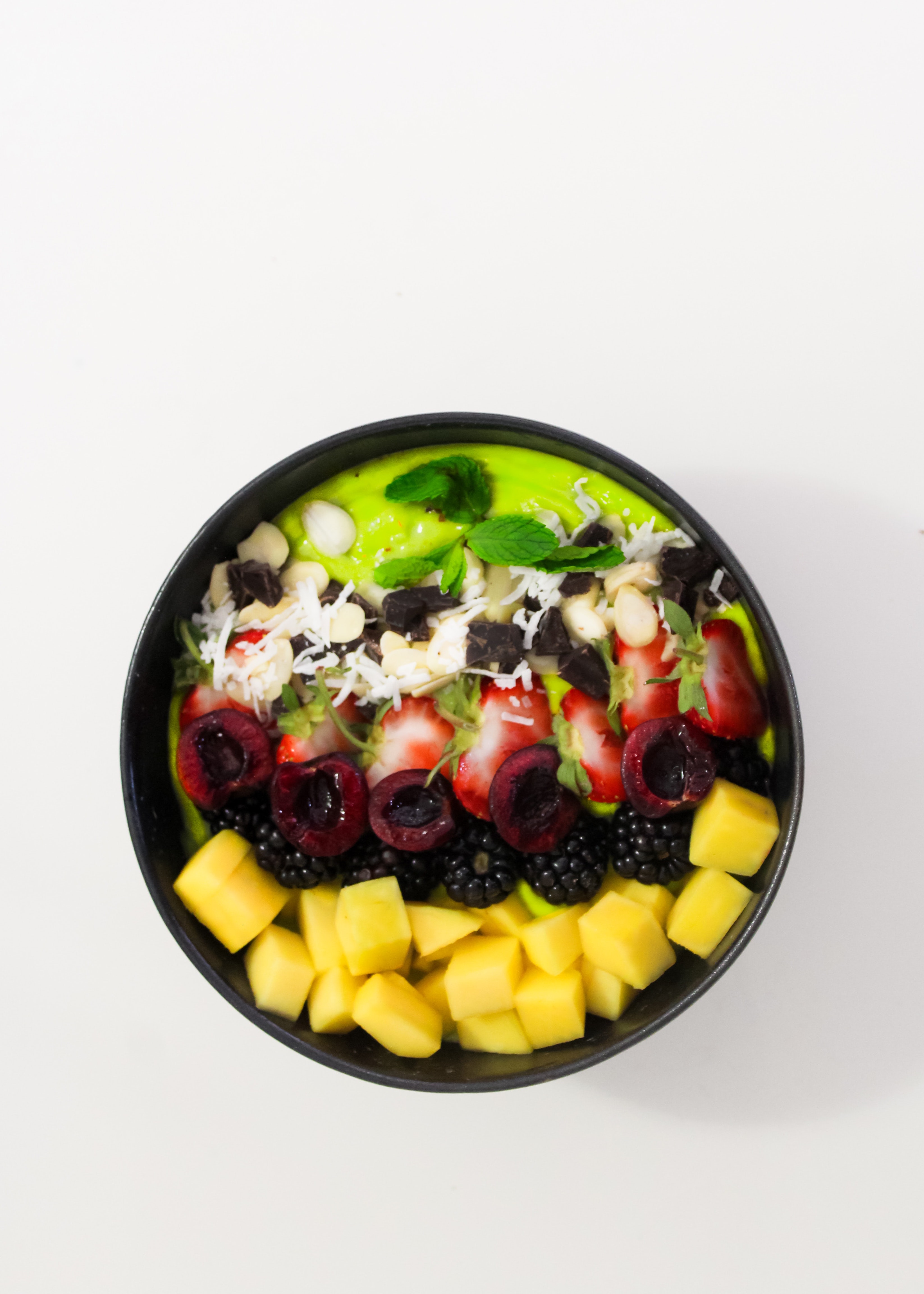 A Smoothie Bowl with Fresh Fruits Topping on a White Surface.