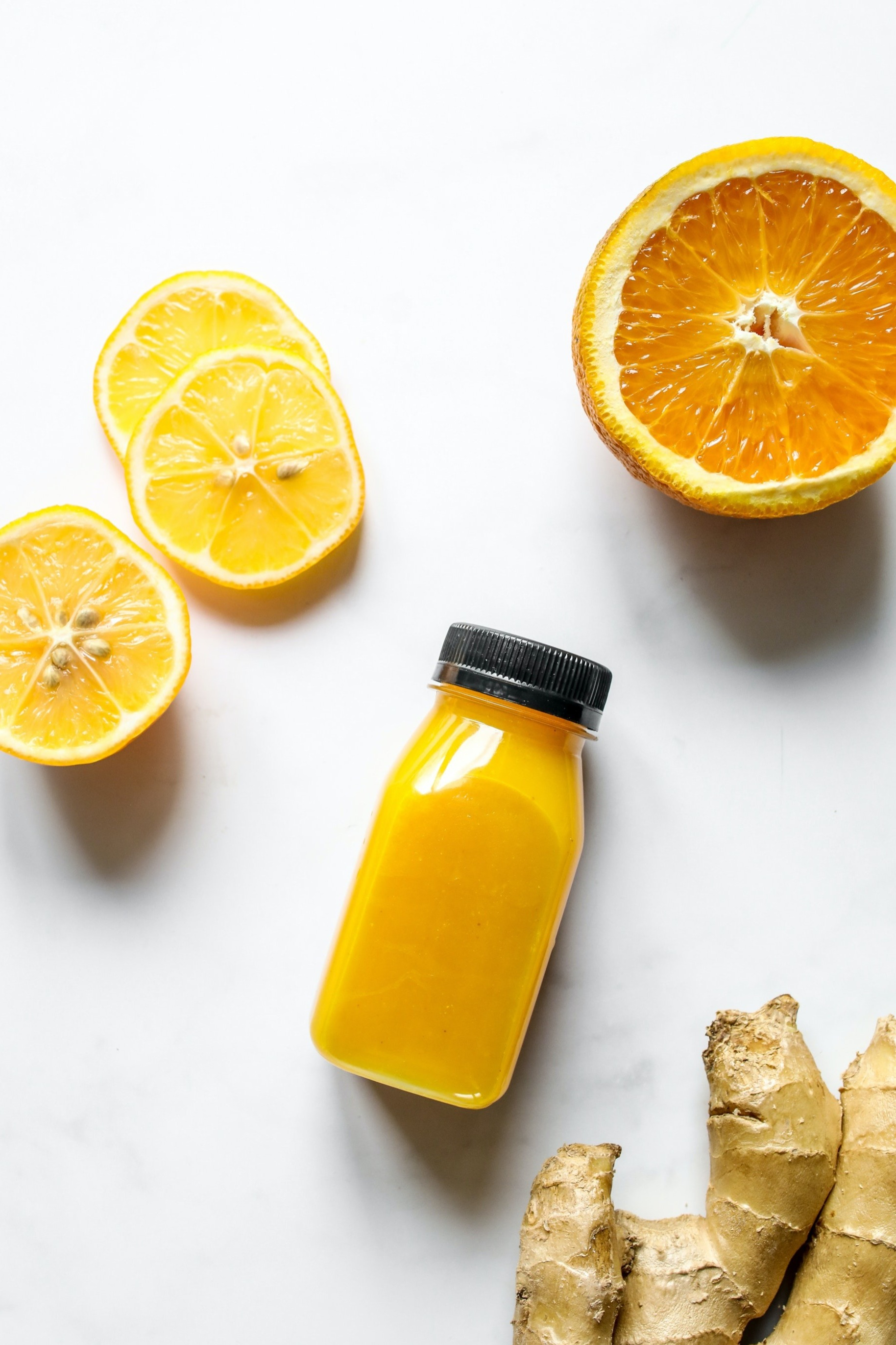 Smoothie with orange, ginger and lemon besides it.