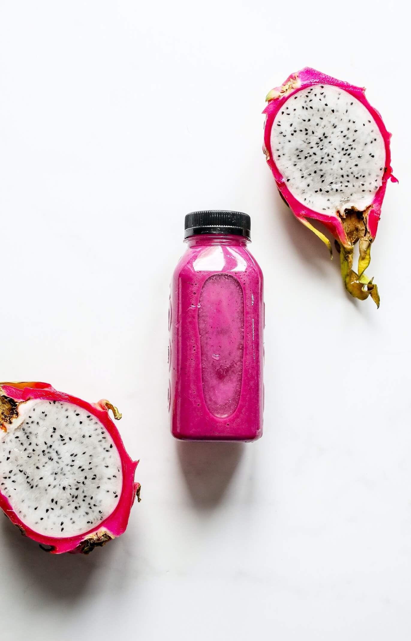 Bottle with Pink Smoothie Between Halves of Dragon Fruit