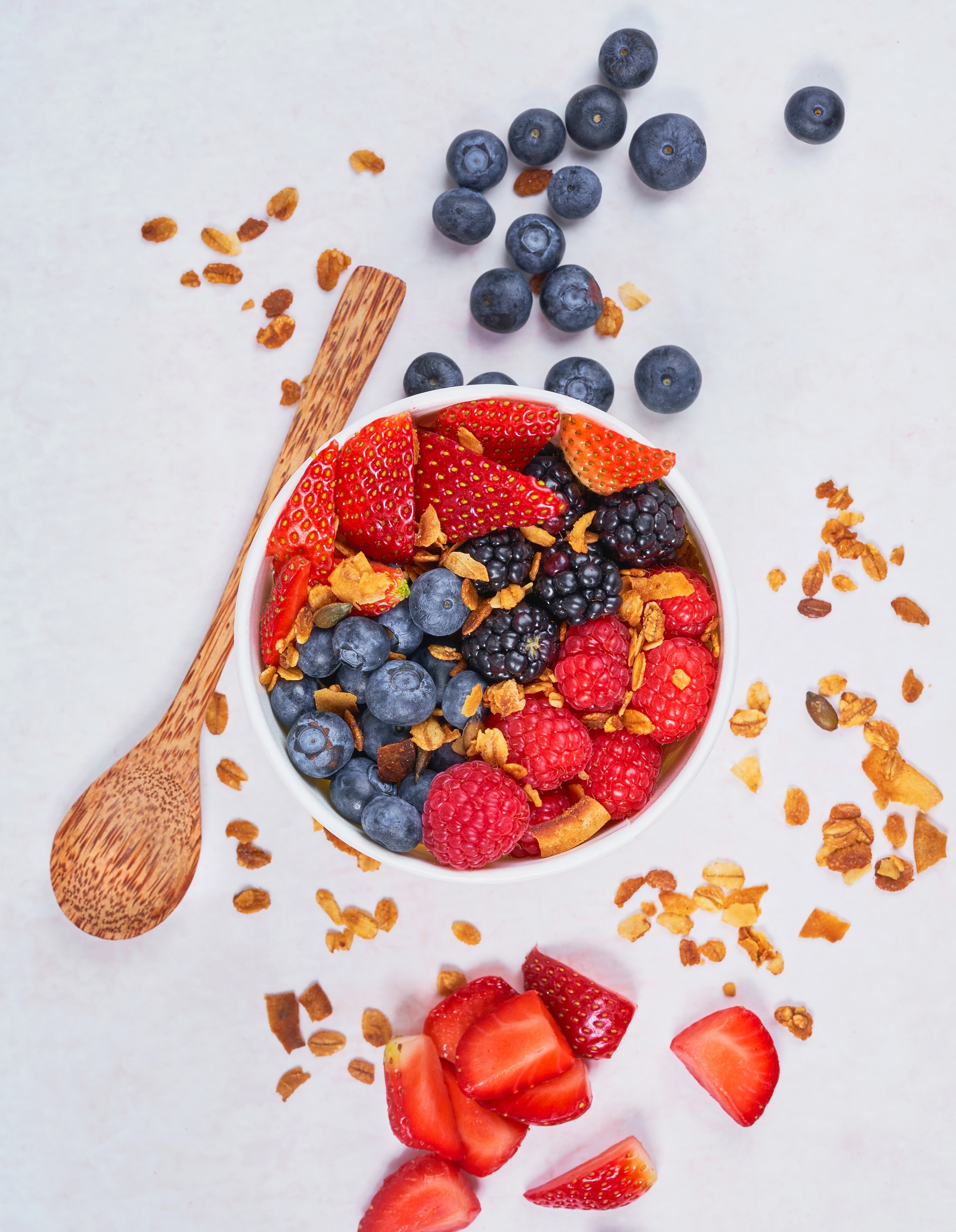 Smoothie bowl with strawberries and blueberries besides it.