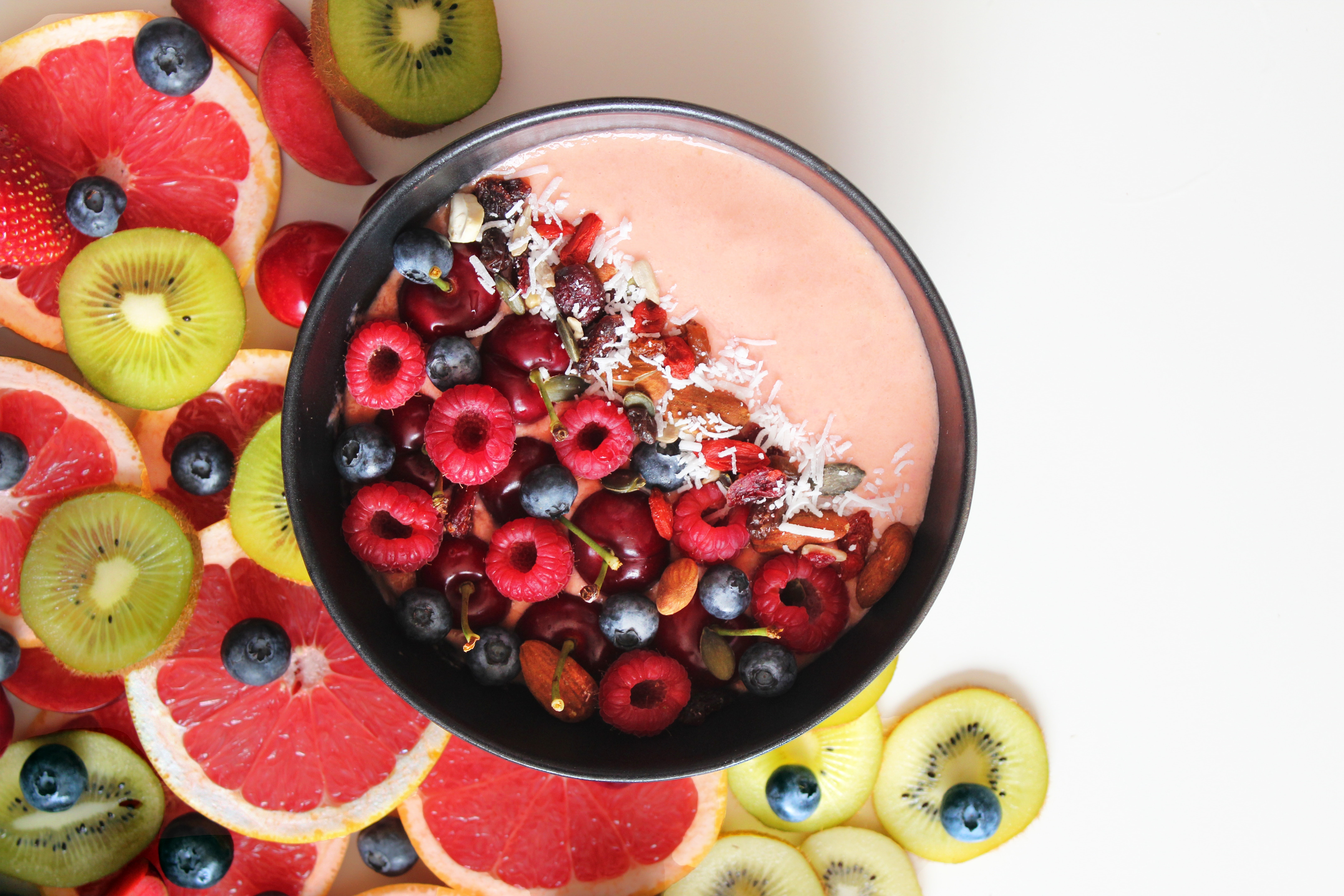 A Smoothie Bowl with Fresh Fruits Topping on a White Surface.