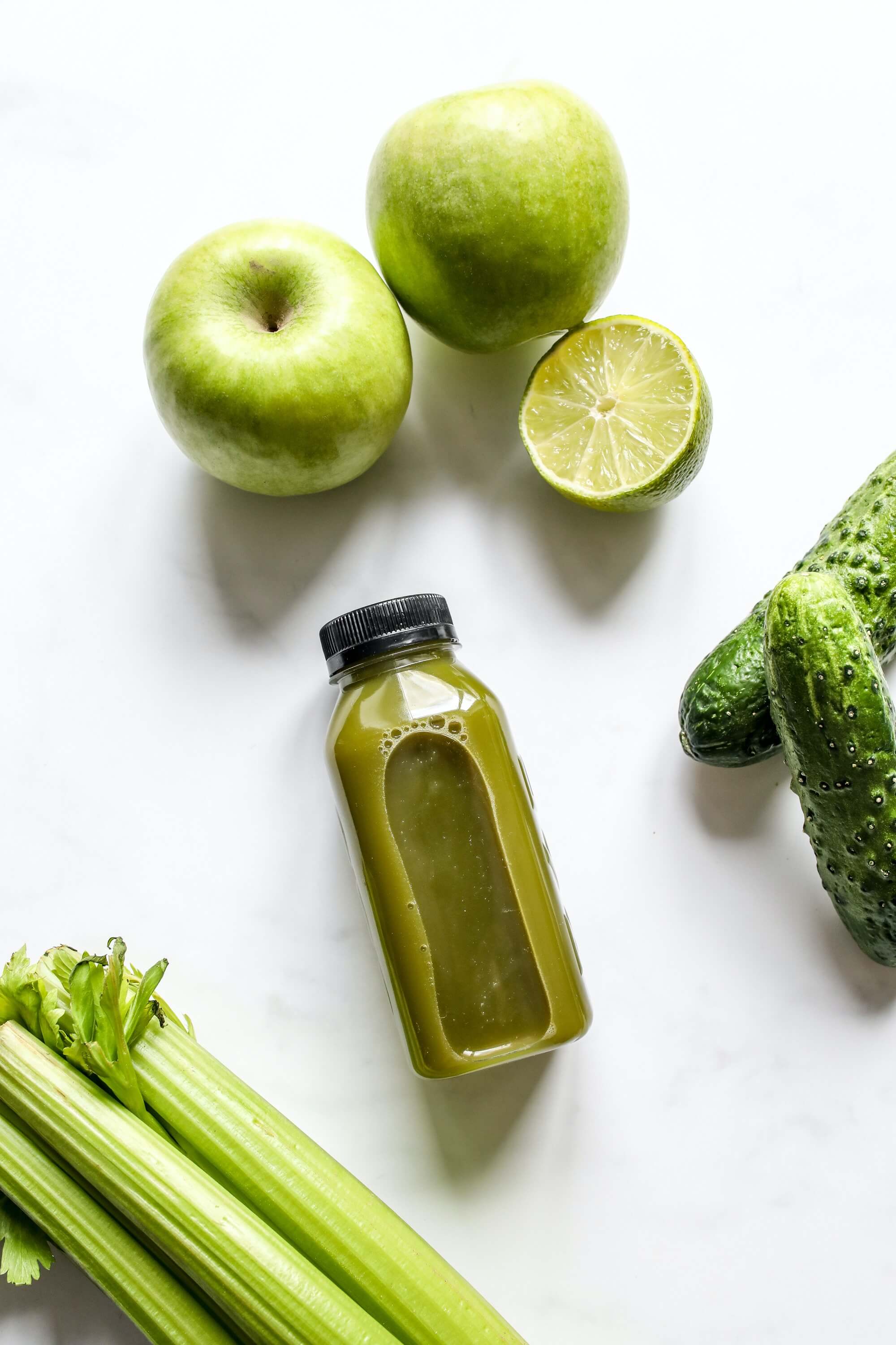 Smoothie with apple, cucumber, lime and celery besides it.